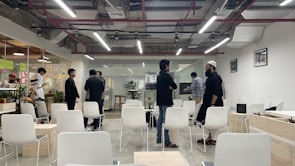 a group of men standing around a room filled with white chairs