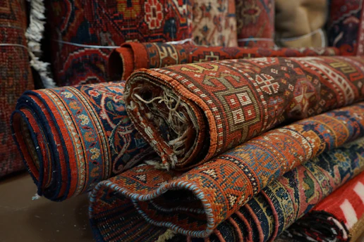 Stacks of beautifully rolled handmade carpets ready for export, showcasing rich textures and colors.