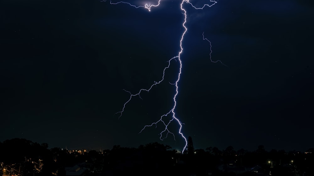 a lightning bolt striking over a city at night