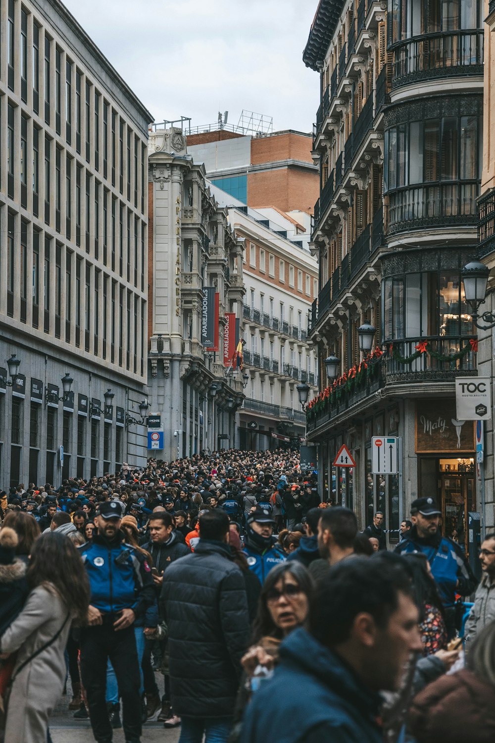 a crowd of people walking down a street next to tall buildings