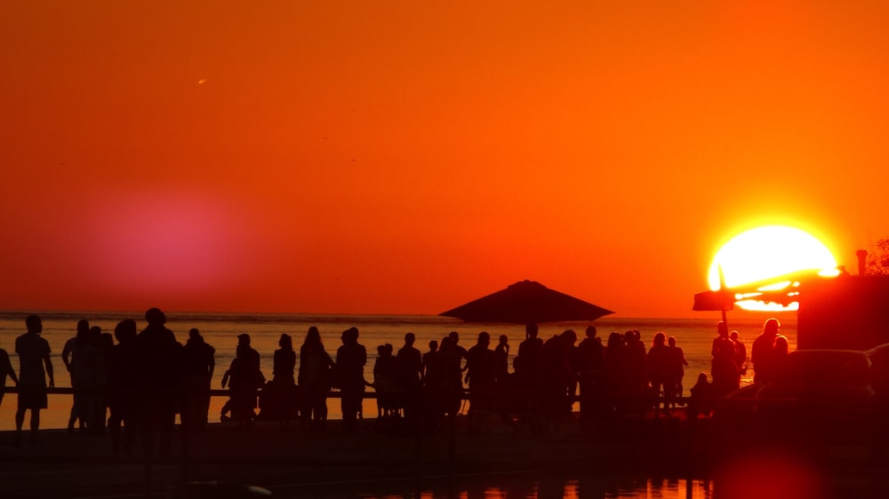 a group of people standing on a beach at sunset