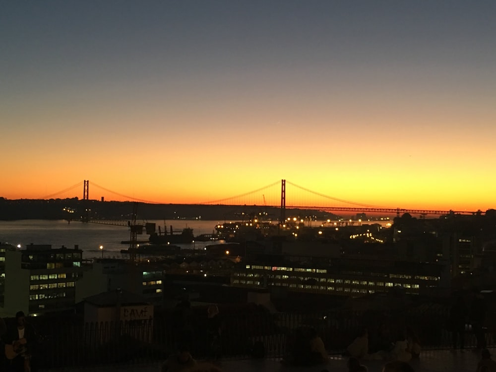 the sun sets over a city with a bridge in the background