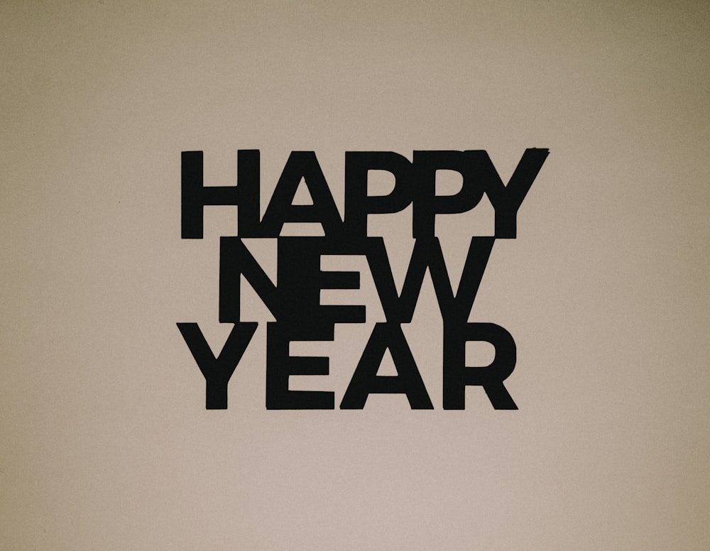 a black and white photo of a clock and a happy new year sign