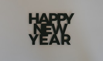 Black bold letters arranged vertically form the phrase 'Happy New Year' on a plain white background.