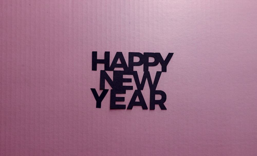 Una foto di un felice anno nuovo scritta in nero su sfondo rosa
