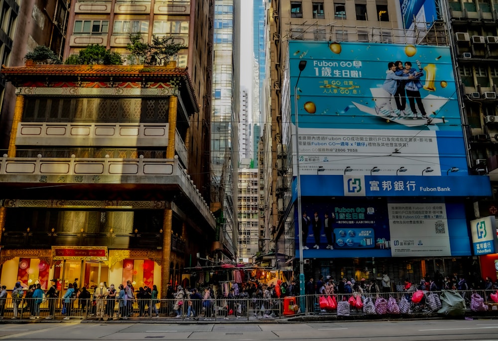 a crowd of people standing on a street next to tall buildings