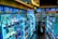 The scene shows a brightly lit drugstore or pharmacy interior with aisles filled with a wide variety of products, including skincare, healthcare items, and everyday essentials. There are informative and promotional signs in multiple languages, mostly focused on East Asian products. Two people are browsing the aisles, one wearing a puffy jacket and the other crouching near the shelves.