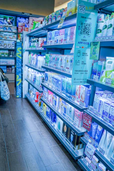 Shelves stocked with pharmaceutical products and medical supplies in a modern pharmacy.