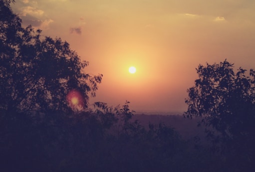 A serene sunset behind a silhouette of an ancient astrological chart, glowing softly in warm yellow and red hues.