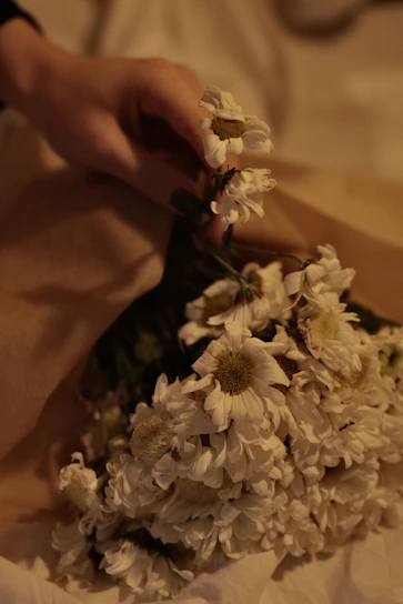 Close-up photo of a soft ivory and clay-toned bouquet wrapped in natural paper and tied with twine under warm natural light.