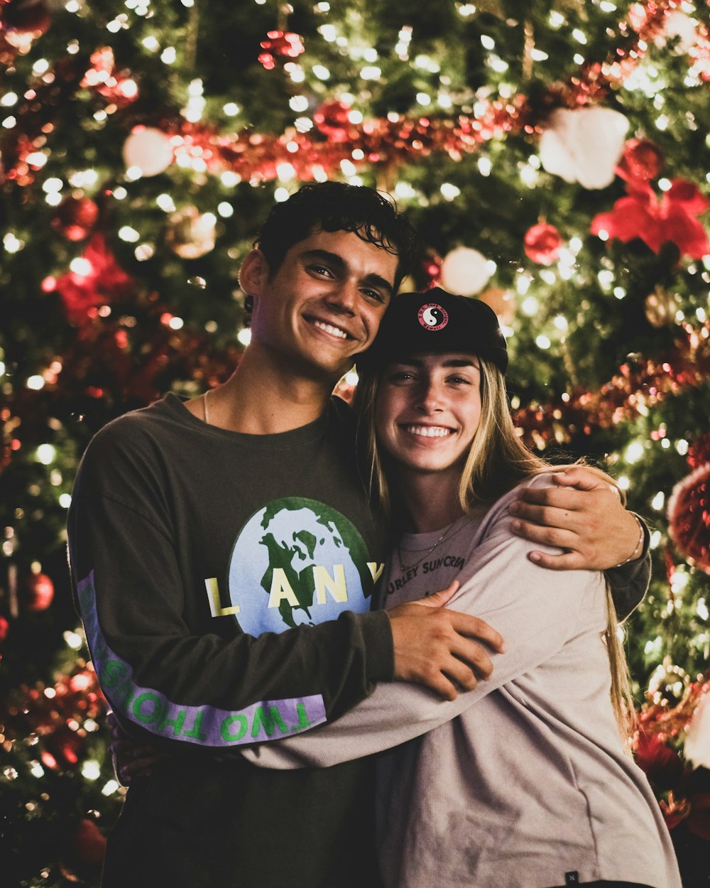 a man and a woman standing in front of a christmas tree