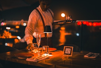 a man standing at a table with wine glasses
