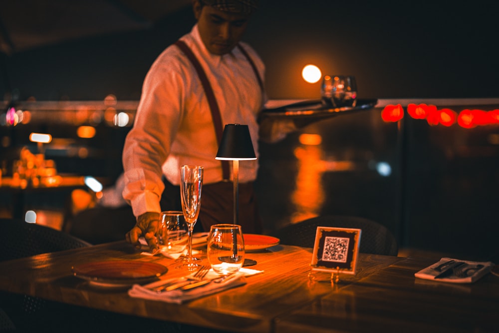 a man standing at a table with wine glasses