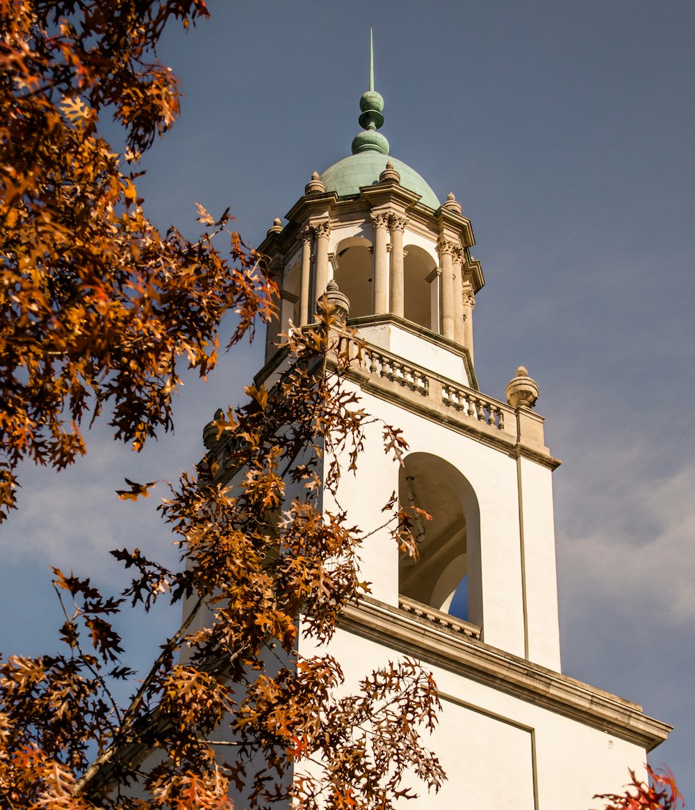 a tall white clock tower with a sky background