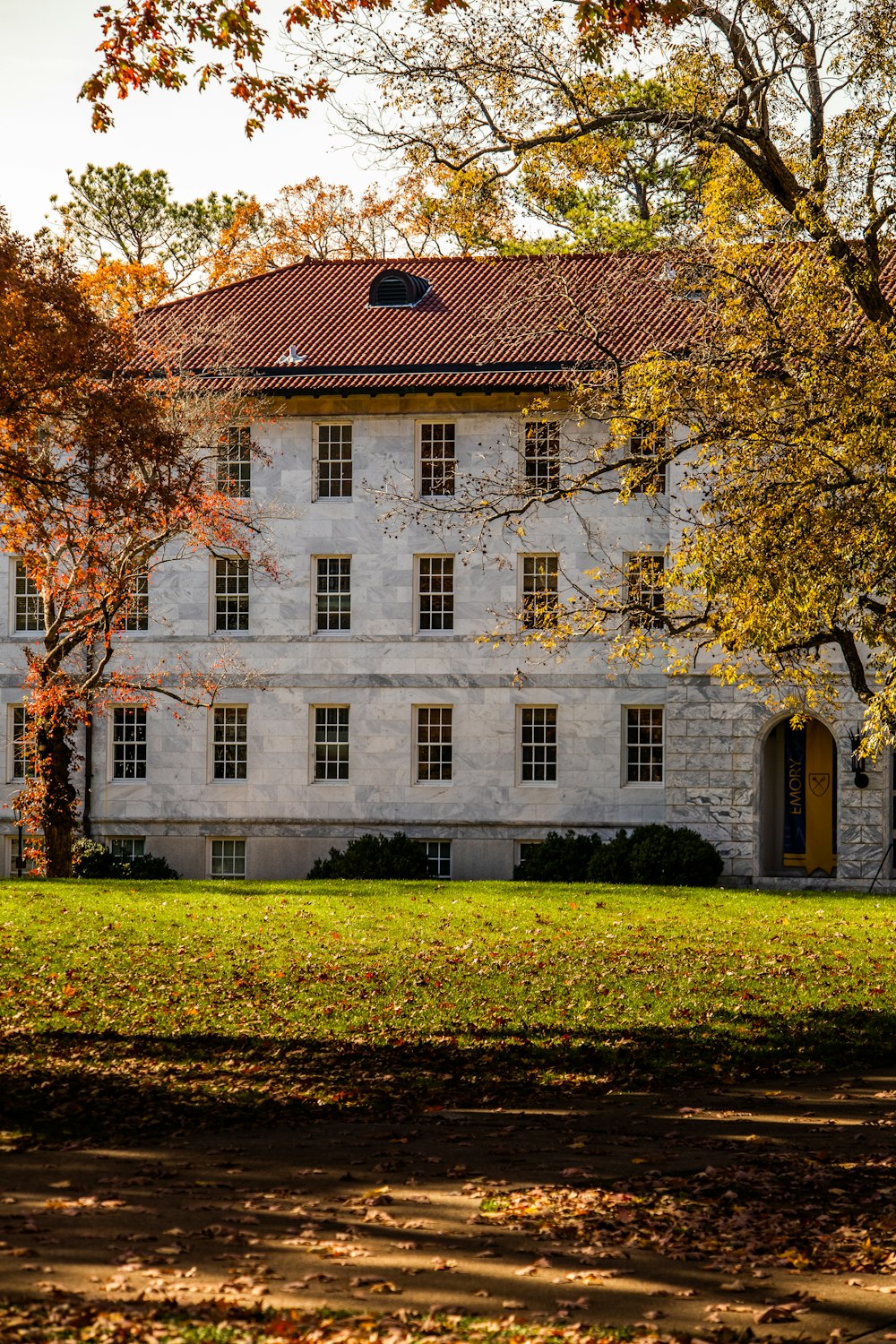 a large white building sitting next to a lush green field