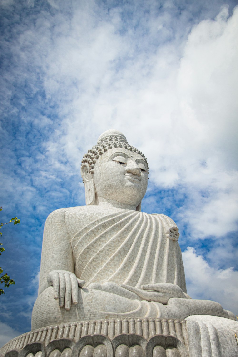 Una grande statua di Buddha seduta sotto un cielo blu nuvoloso