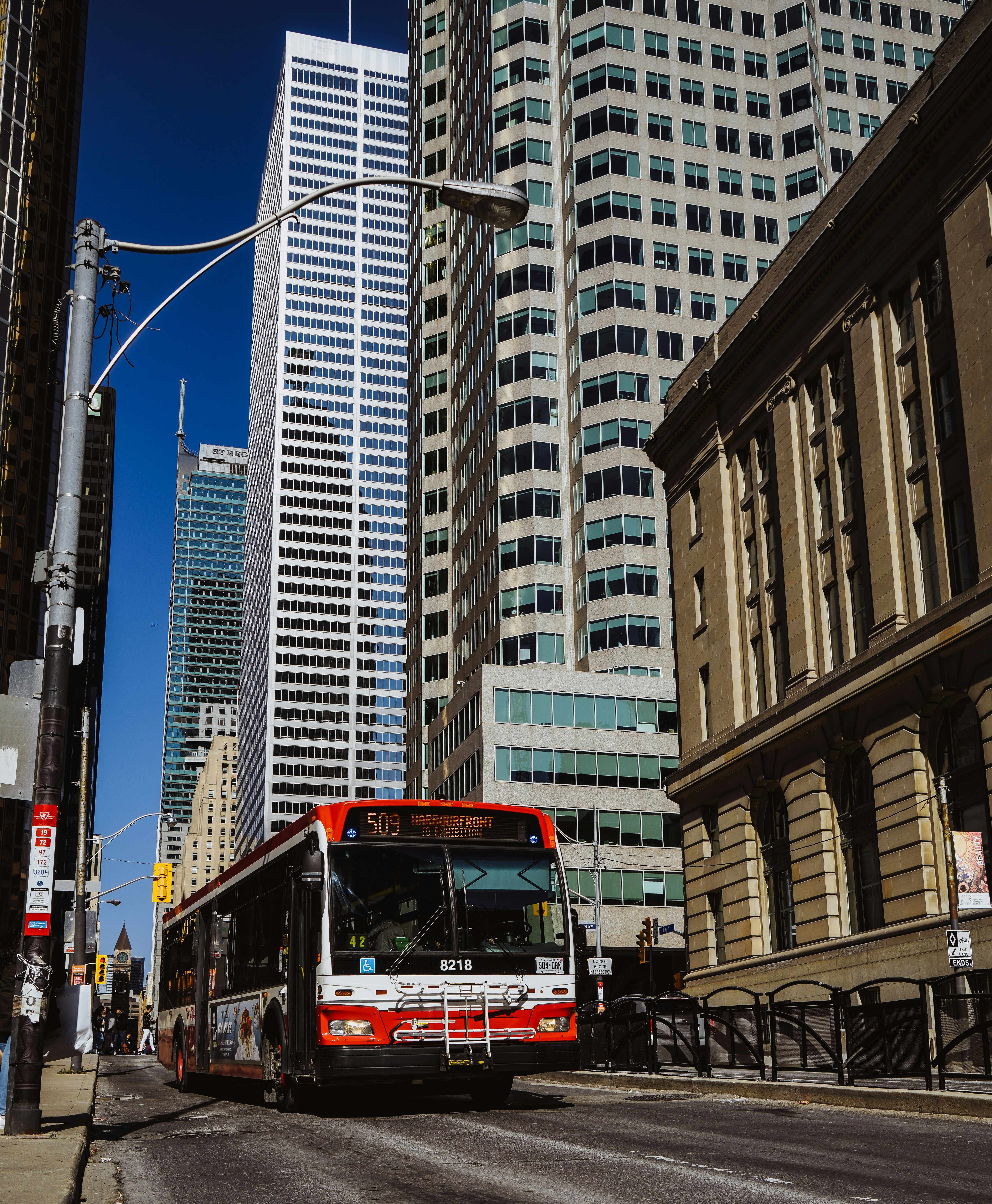 a red and white bus driving down a street next to tall buildings