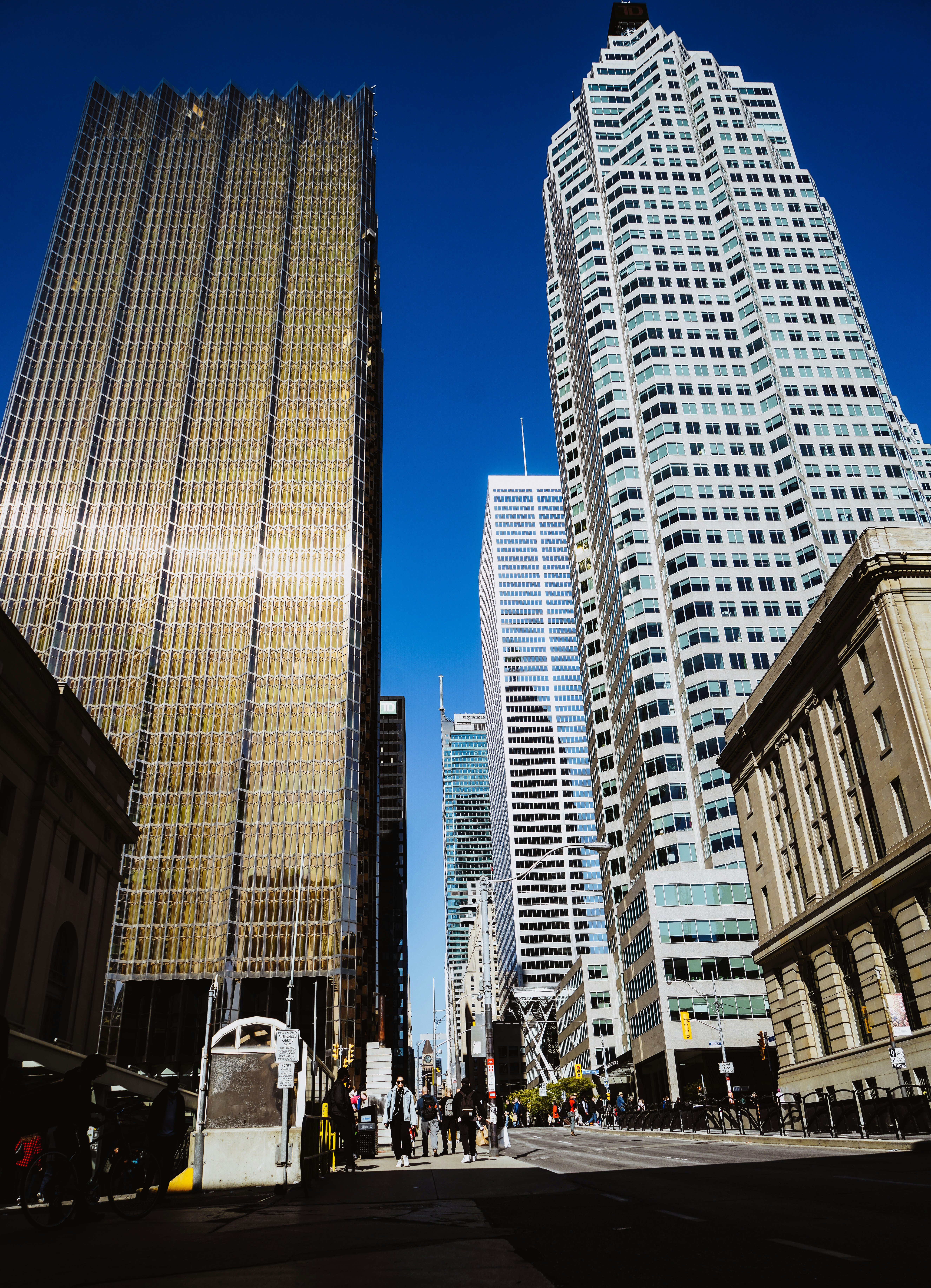 a group of people walking down a street next to tall buildings