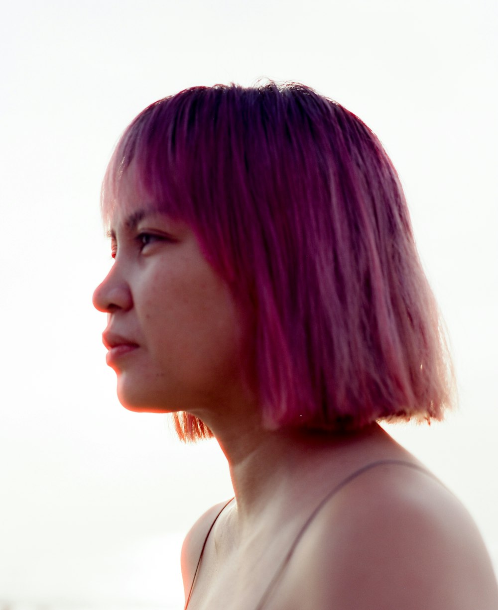 a woman with pink hair is looking off into the distance