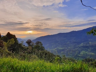 A scenic view of lush green hills and a peaceful property in Jarabacoa at sunset.