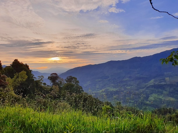 A scenic view of lush green hills and a peaceful property in Jarabacoa at sunset.