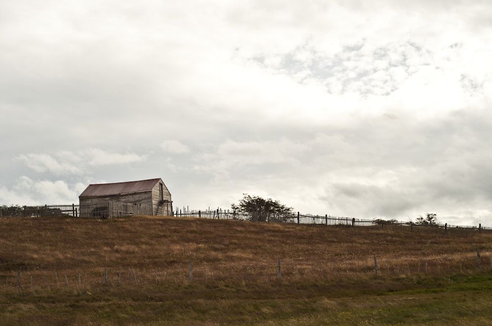 a barn on a hill with a fence around it