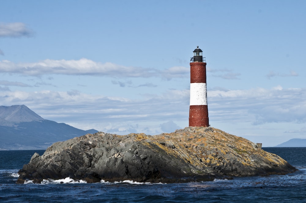 a red and white lighthouse sitting on top of a rock