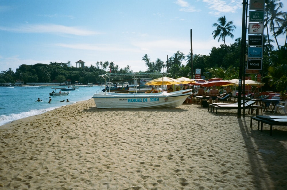 a boat on the beach with people swimming in the water