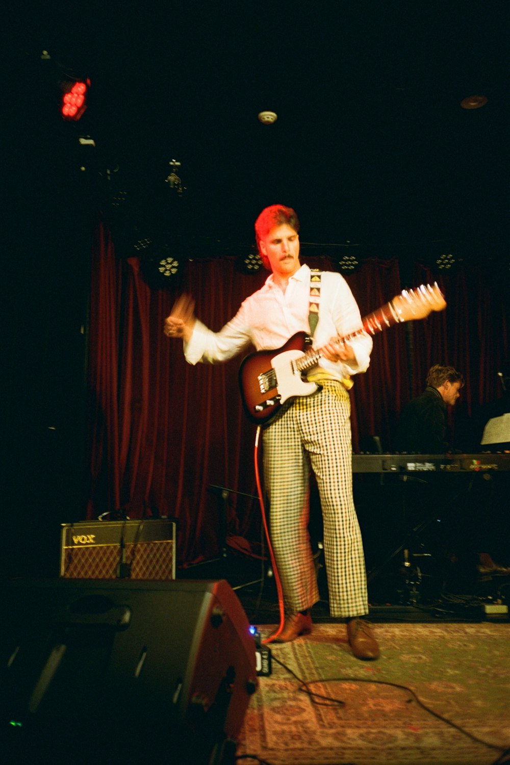 a man standing on a stage with a guitar
