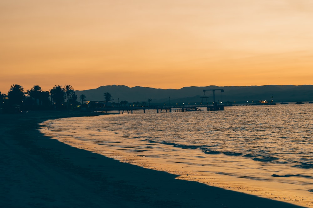 a beach at sunset with mountains in the background