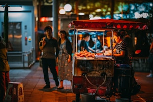 a group of people standing around a food cart