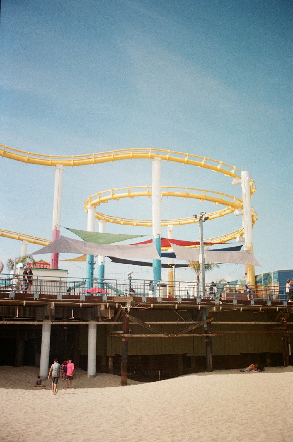 a roller coaster on a beach with people walking around