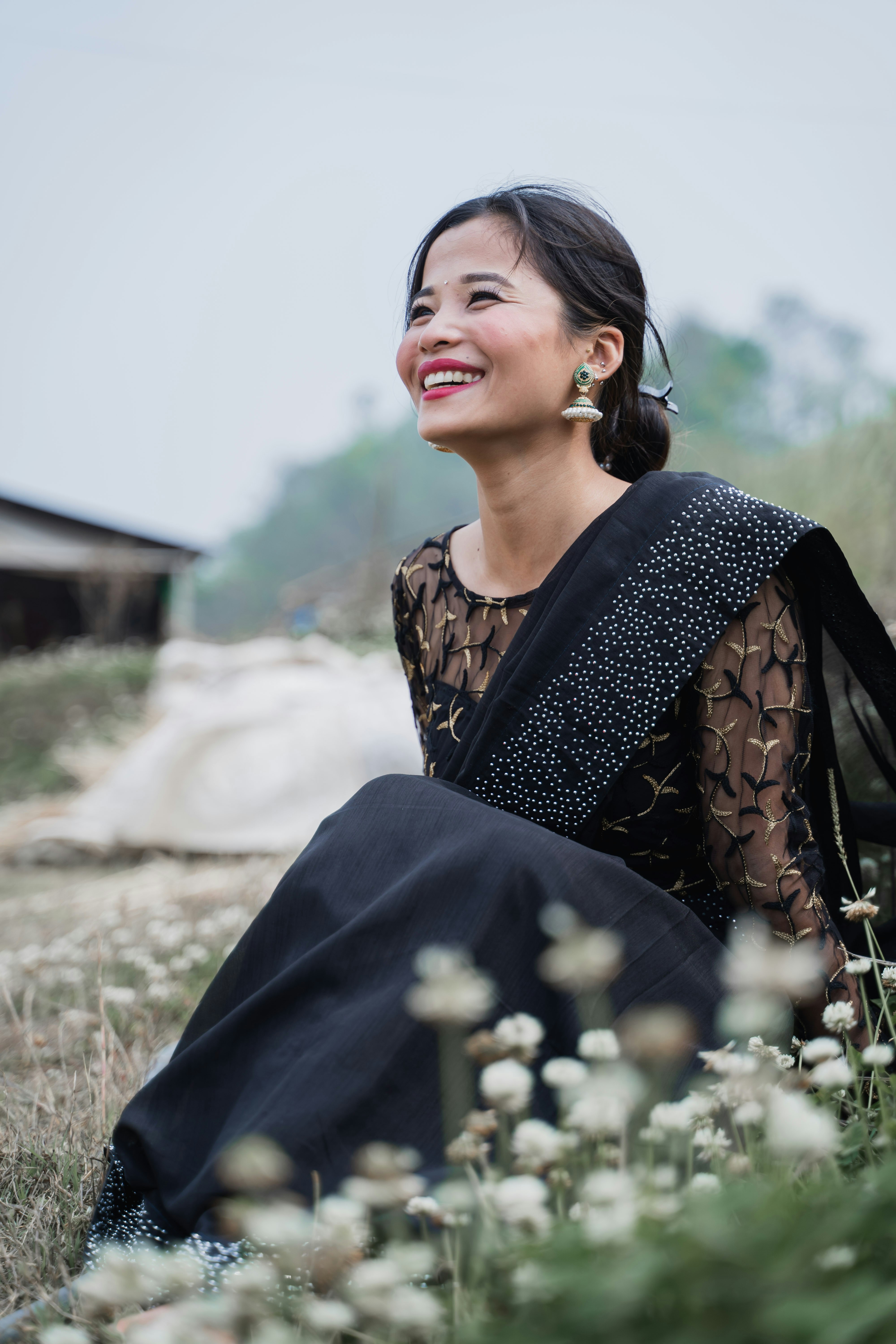a woman sitting in a field of flowers smiling