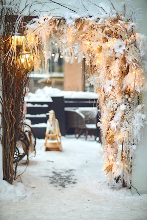 An elegantly decorated wedding arch glowing with champagne and gold tones, framed by luxurious drapes.