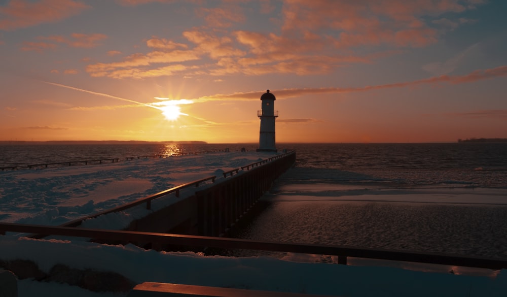 a light house sitting on top of a pier next to the ocean