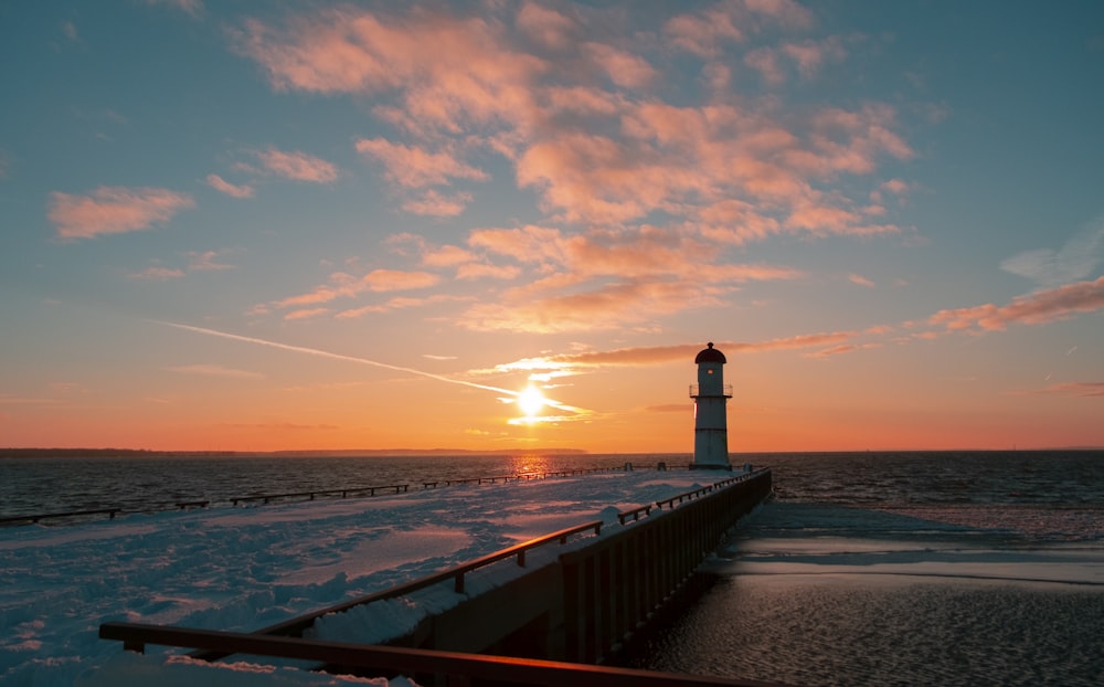 a light house sitting on top of a pier next to the ocean