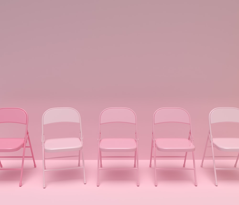 a row of pink and white chairs against a pink background