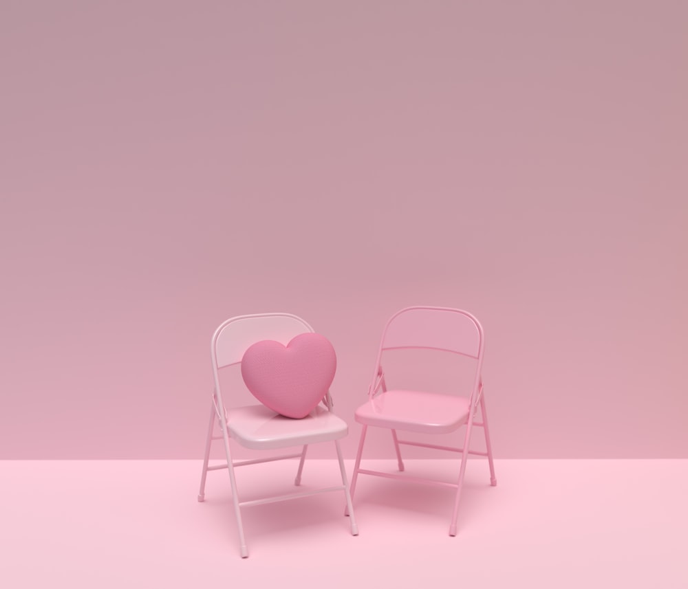 une chaise rose et une chaise blanche avec un oreiller en forme de cœur