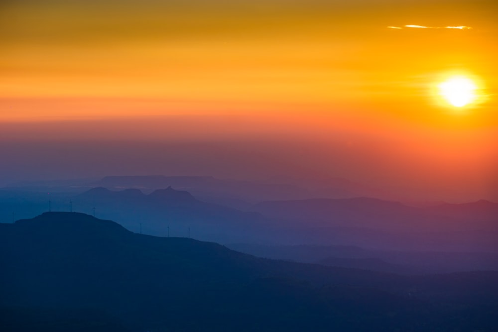 the sun is setting over a mountain range