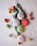A collection of Christmas-themed decorations including fabric ornaments with embroidered designs like snowflakes and a snowman, green tinsel, shiny baubles in red and green, small gold-wrapped gifts, a decorative Santa figure, small bells, and a translucent snowflake.