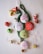 A collection of Christmas-themed decorations including fabric ornaments with embroidered designs like snowflakes and a snowman, green tinsel, shiny baubles in red and green, small gold-wrapped gifts, a decorative Santa figure, small bells, and a translucent snowflake.