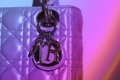 Close-up of a playful silicone charm dangling from a light lavender bag strap.