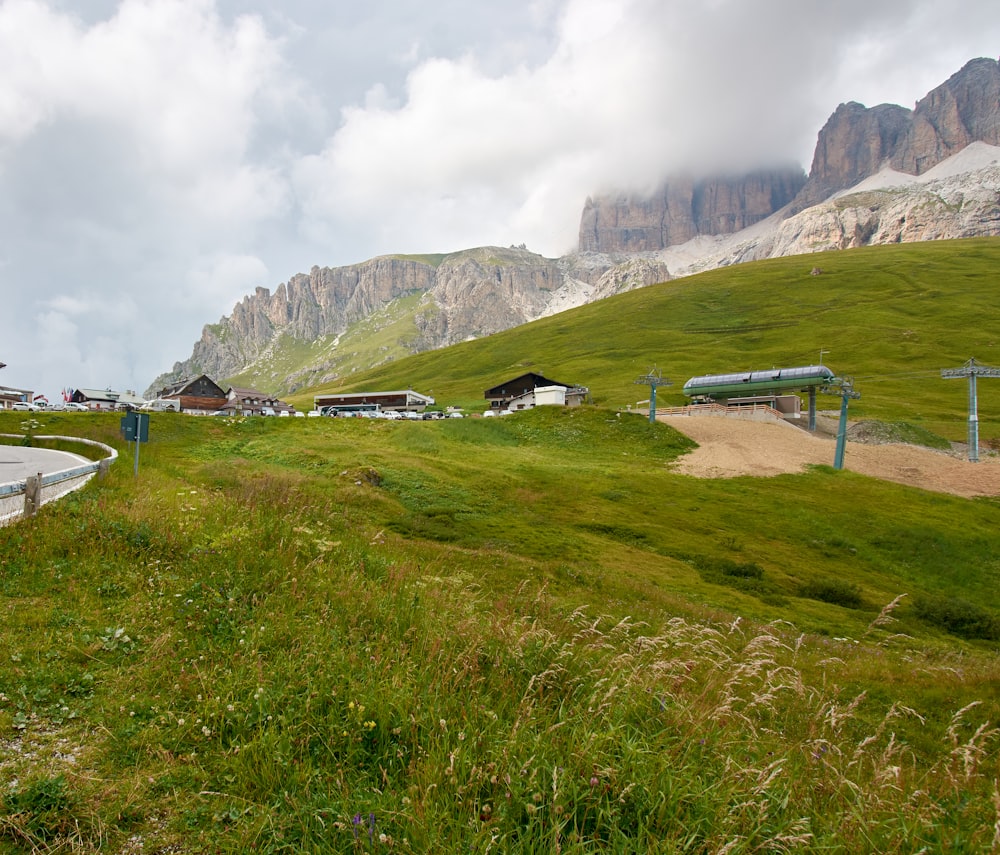 a grassy field with a road and a mountain in the background