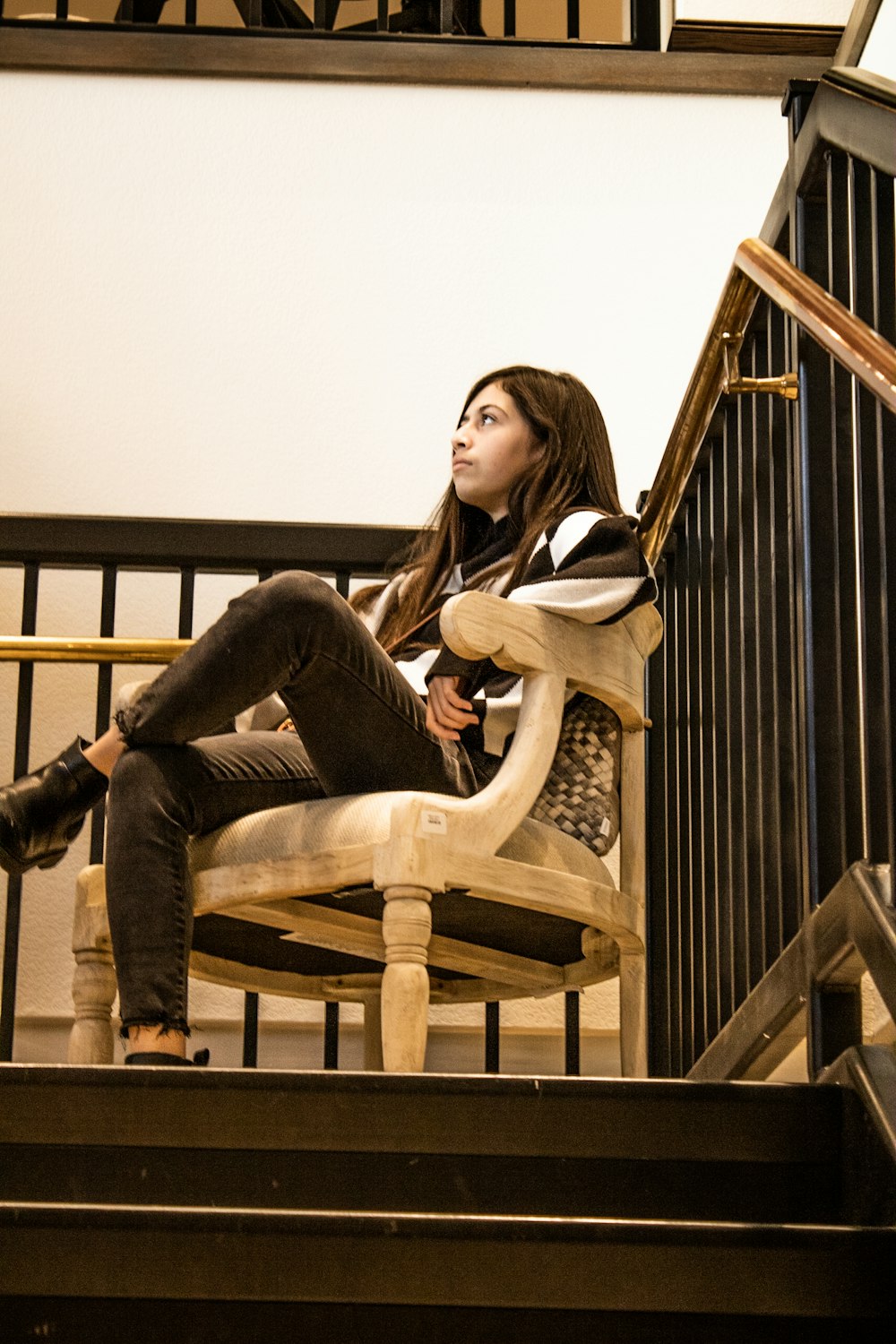 a woman sitting on top of a wooden chair