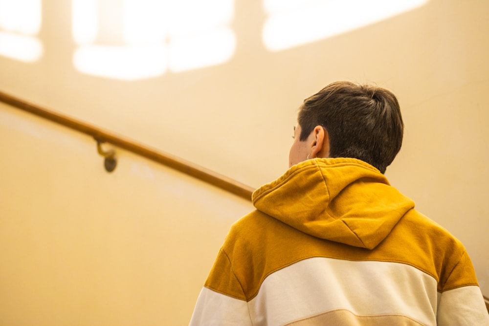 a young boy wearing a yellow and white jacket