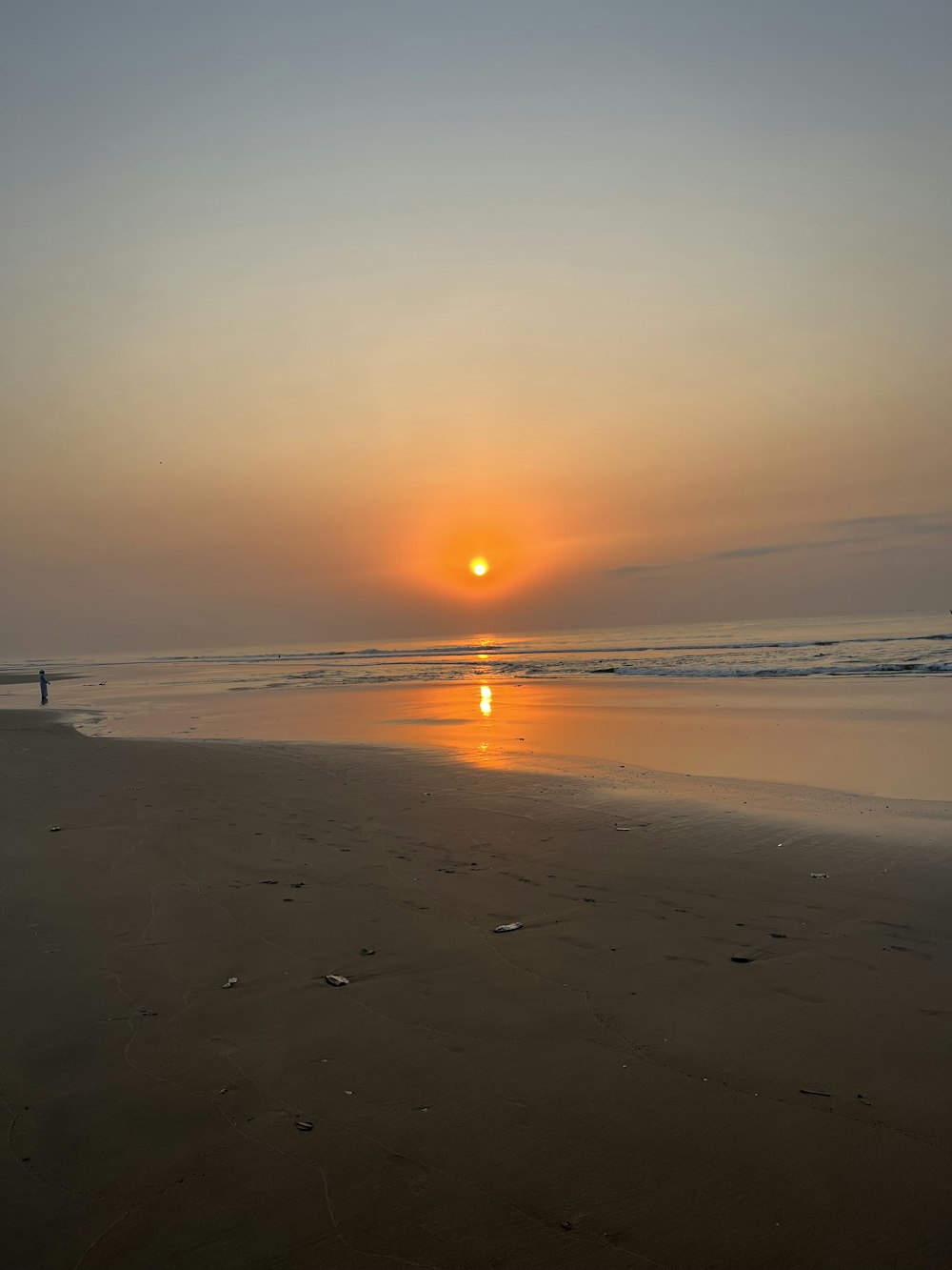uma pessoa andando em uma praia ao pôr do sol