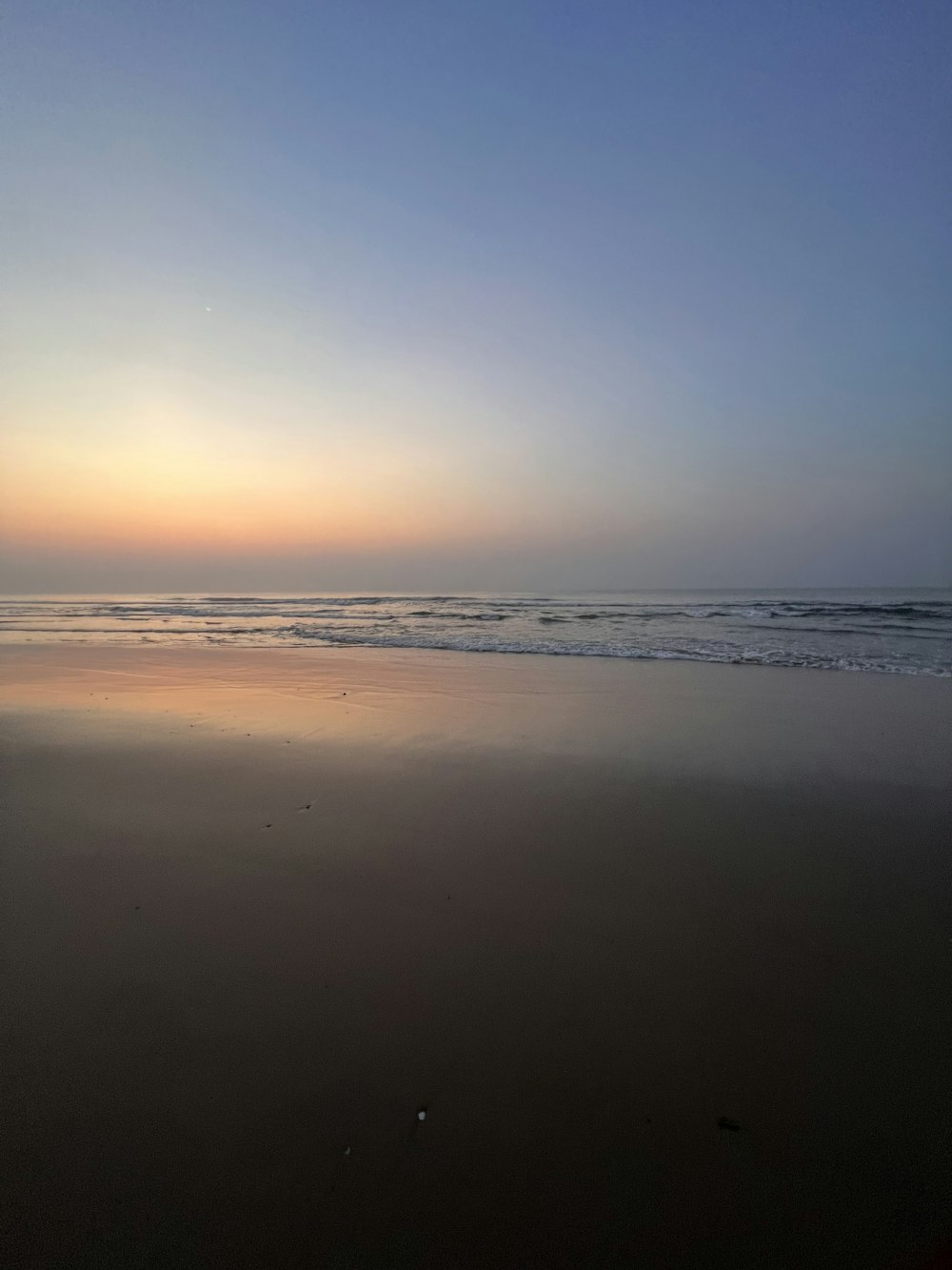 the sun is setting over the ocean on the beach