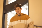 A caring staff member assisting a young person with a supportive smile in a bright, open space.