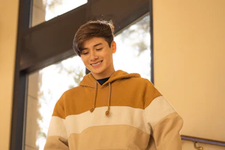 A young person wearing the light blue and black harlox streetwear set, smiling while typing on a laptop in a bright, minimalistic room.