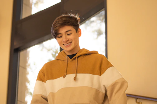 A young person wearing the light blue and black harlox streetwear set, smiling while typing on a laptop in a bright, minimalistic room.